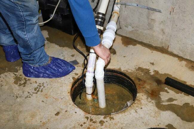Чоловік ремонтує водозбірний насос у затопленому підвалі