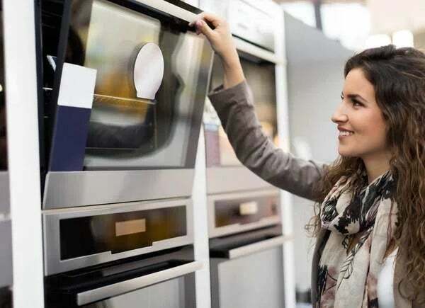 Vrouw die een nieuwe oven koopt in de apparatenwinkel.