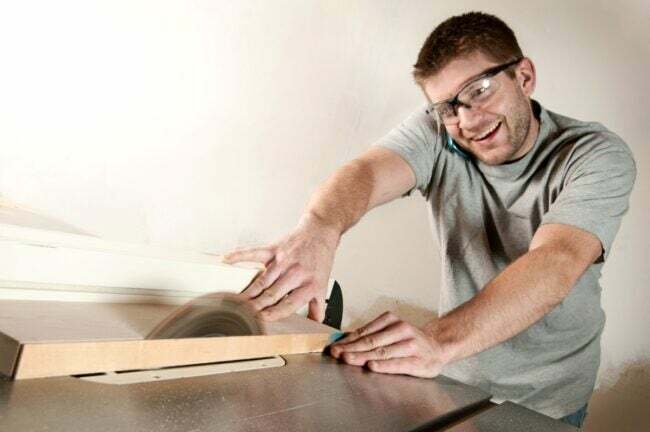 最も危険な電動工具 - テーブルソーを使用して電話をしている男性