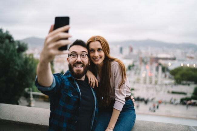 çift ​​tatildeyken şehir manzarasının önünde selfie için poz veriyor