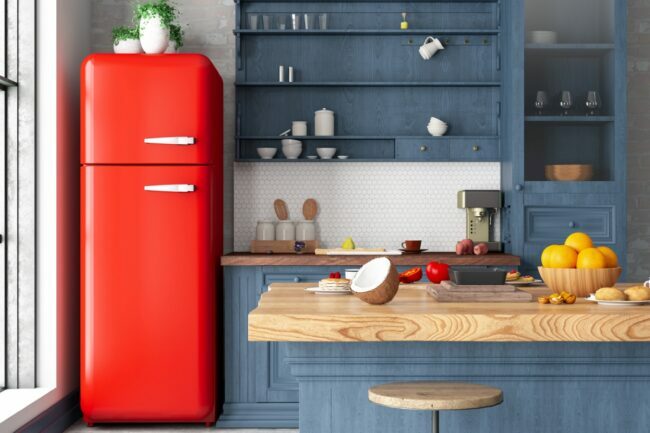 Køkken med blå skabe, slagterblokdiske og et rødt vintagekøleskab