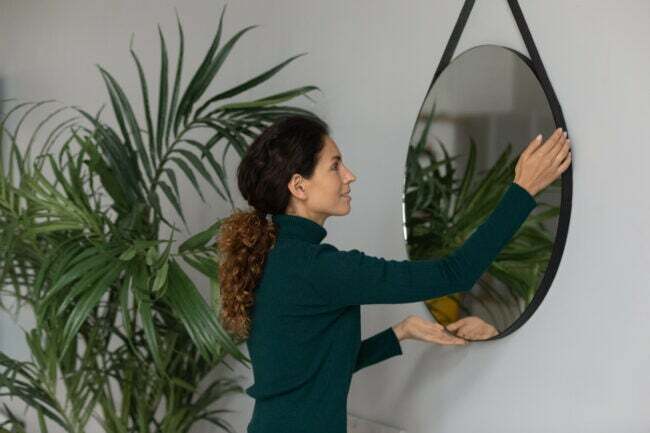 iStock-1297735499 Home Depot shoppingkvinna som hänger upp spegeln i huset