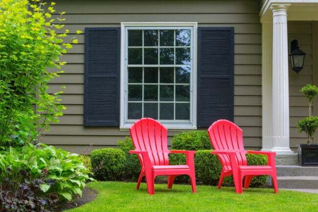 dve červené adirondacké stoličky v prednej časti sivého domu
