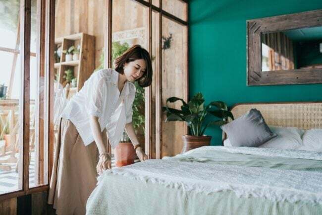 jak zostać gospodarzem Airbnb — kobieta ścieli łóżko dla gości
