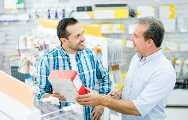 Homem casual fazendo compras em uma loja de eletrônicos e conversando com o vendedor