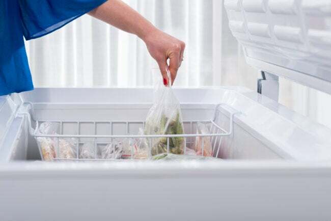 Seorang wanita menaruh beberapa sayuran di lemari es
