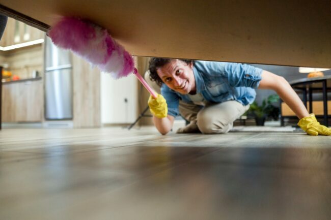 Hombre limpiando telarañas debajo de la cama