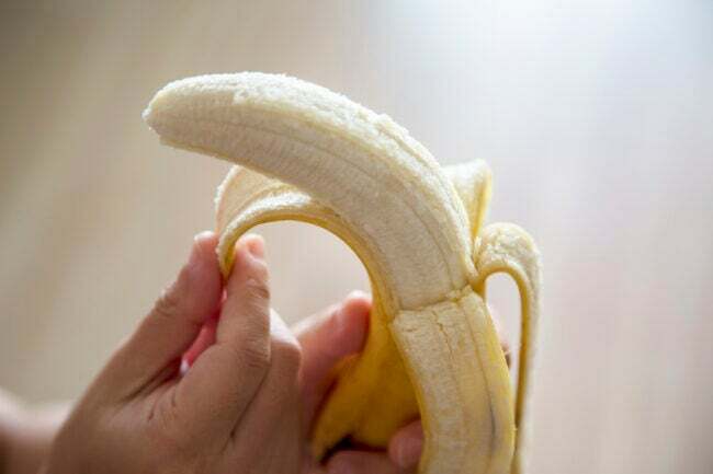 zblízka na ruky šúpajúci banán