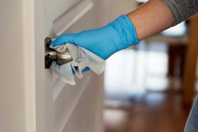 Limpando a maçaneta da porta com pano desinfetante