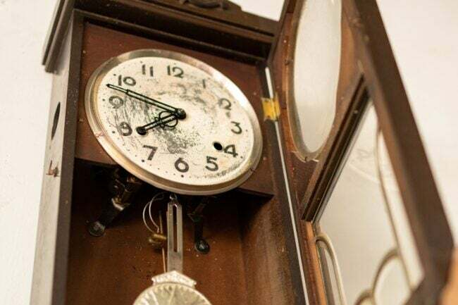 Relógio de pêndulo antigo com um rosto quebrado