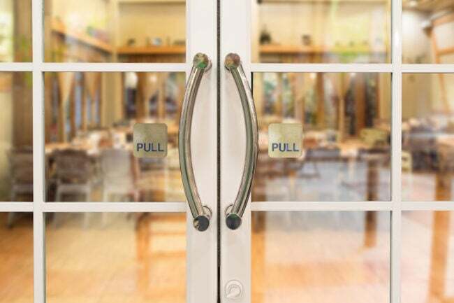 sklenené dvojkrídlové dvere do reštaurácie s ozdobnými kľučkami a nápismi na každé dvere